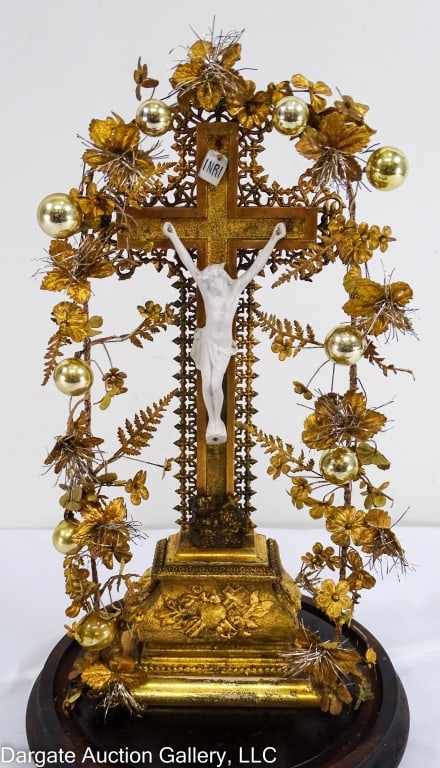 VICTORIAN CRUCIFIX IN DISPLAY DOME: Wooden crucifix with a parian ware bisque figure of Jesus on the cross. An arch of handwired gilt linen flowers. All under a glass display dome. / Measures: 16"H x 7" diameter / Condition: Wear approp