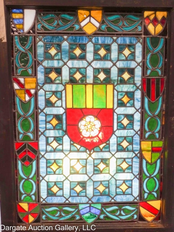 ENGLISH TUDOR STYLE STAINGLASS WINDOW: Nice English Tudor style stain glass window with a large shield in the center and ten small shields around the edges. Blues/greens/reds/white and amber glass. Nice wooden frame. Frame 23.75" x 32.5" x