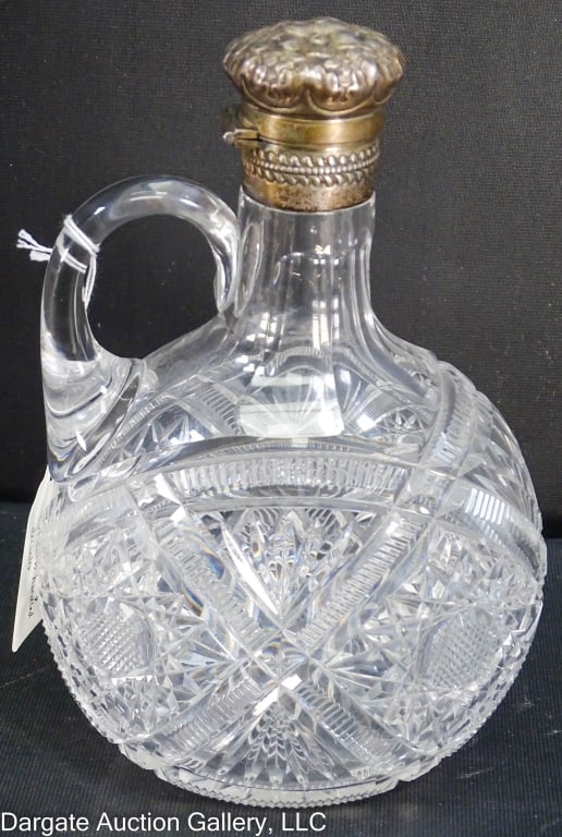 CUT GLASS HANDLED DECANTER W/ STERLING LID GORHAM: An ovoid cut glass handled decanter with a locking sterling lid in a floral pattern by Gorham. Marked [Gorham sterling]. / Measures: 8"Hx5.5"Wx4"D / Condition: A few scattered flea bites.