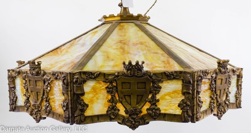 FEUDAL STAIN GLASS PANEL PENDANT: Feudal style large cast irion and brass stain glass panels. Pendant hanging light. 8 large butterscotch slag glass panels on top. Side panels have a shield with a cross topped with a crown and surroun