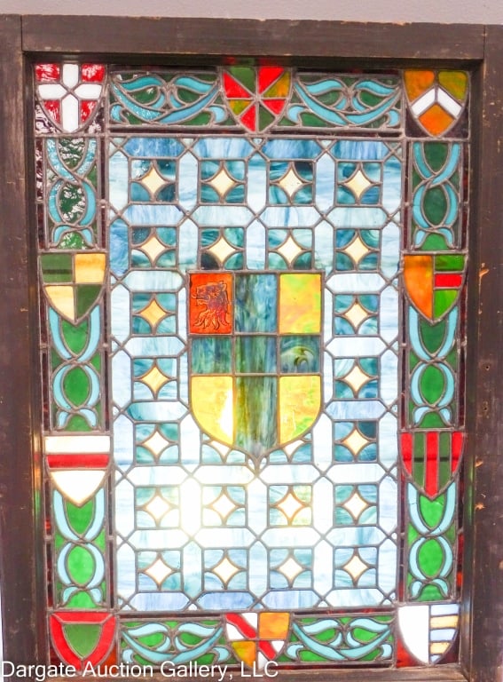 ENGLISH TUDOR STYLE STAINGLASS WINDOW: Nice English Tudor style stain glass window with a large shield with a lion in one panel and ten smaller shields around the edges. Blues, greens, amber, white, and red. Nice wooden frame. Frame 23.75"