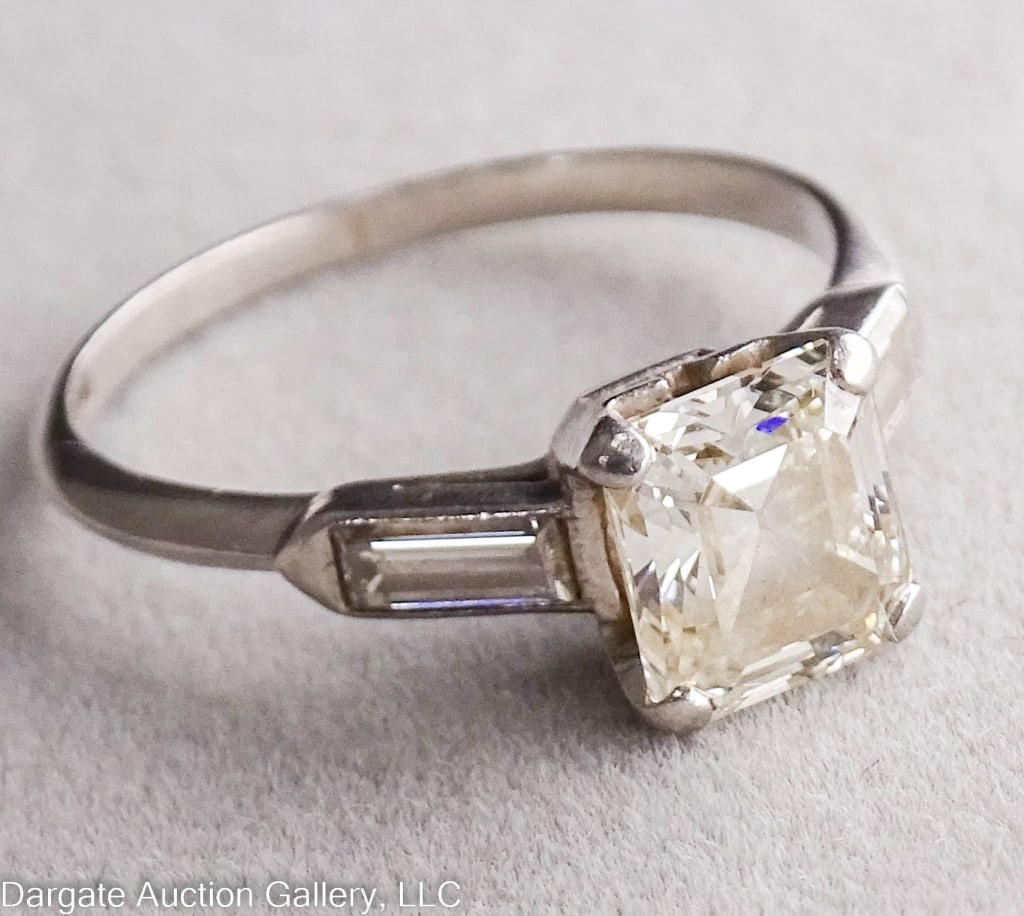 PLATINUM AND DIAMOND RING: 1.25-1.50 ct Center Cushion cut diamond, flanked by 2 baguettes (.25 cttw) / yellow tint to diamond / marked 900 PLAT 100 IRID / Weight: 3.3g / Measurements: Size 6, 1.5-1.75 cttw/ ONLINE PAY MSG ****