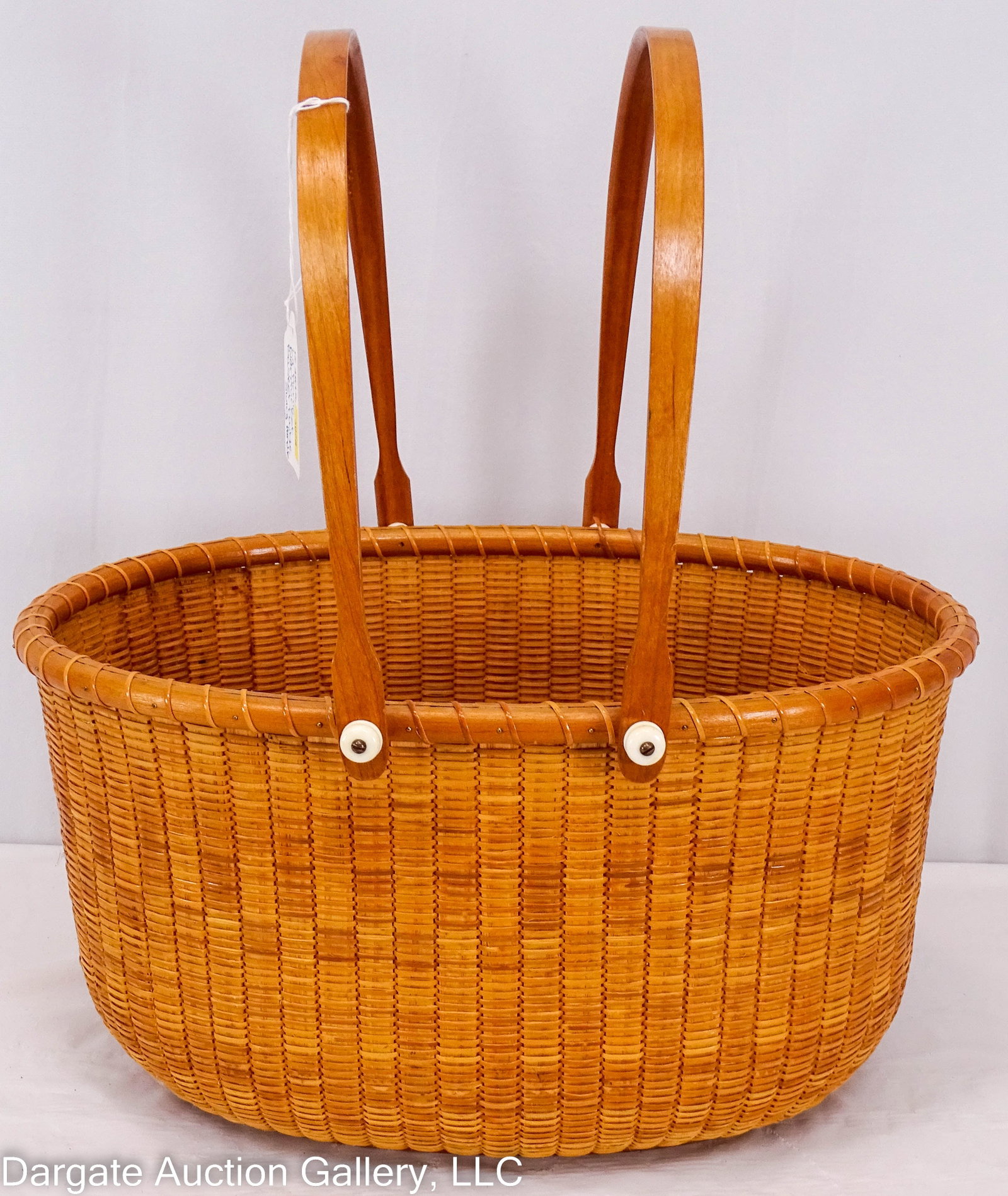 LARGE NANTUCKET PICNIC BASKET DOUBLE SWING HANDLE: Circa 1992, large oval basket with double swing handles and cherry wood base, signed "D.J.S. 7/92 B.P.S" / Measurements: 8"H x 15"W x 11"D, 17" top of handle / Provenance: From the descendants of Loll