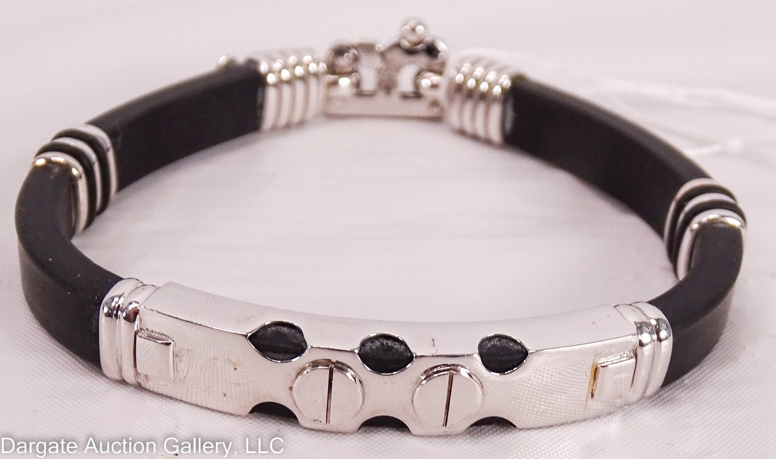 BRACCIO 14k WHITE GOLD AND RUBBER BRACELET: Black rubber band with 14k white gold wraps and B-shaped closure [BRACCIO][585] / Weight: Total Gross Weight: 27.1g / Measurements: 8.5" long / Provenance: From the descendants of Lollie Oliver, Pitts
