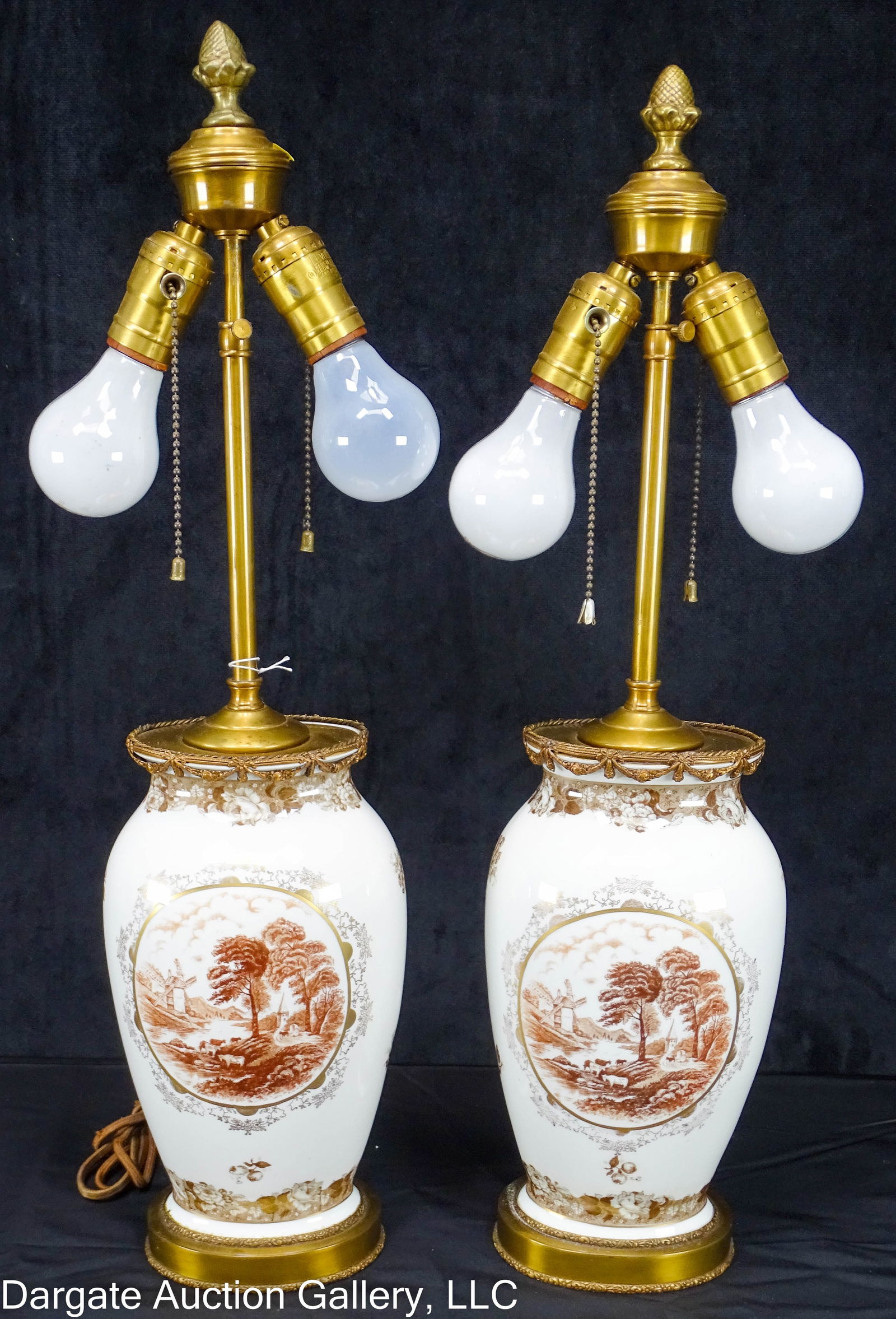 PAIR BRONZE MOUNTED PORCELAIN TRANSFERWARE LAMPS: Pair of brown transferware table lamps fitted into bronze mounts, each with two-bulb pull chain fixture and acorn finials. Lamp stem is adjustable up and down. Patoral scenes of cows and a windmill /