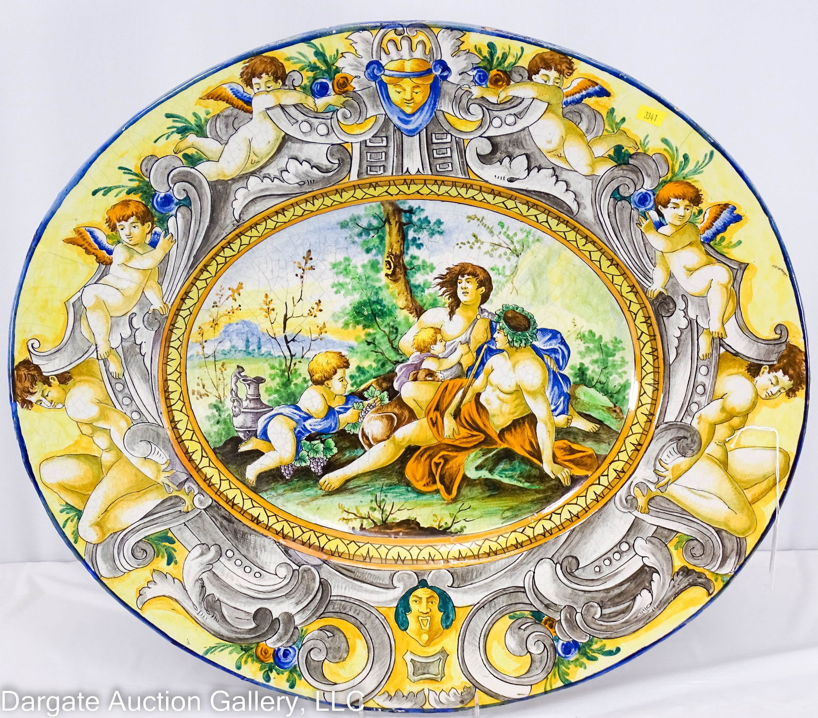 IMPRESSIVE ITALIAN MAILOICA/MAJOLICA CHARGER: An impressively sized Bacchanal charger, tin glazed Majolica pottery, marked on back [DA] or [AD] intertwined, and [ITALIA] / Measures: 4"H x 24"W x 21.5"D / Condition: Crazing and hairlines and glaze