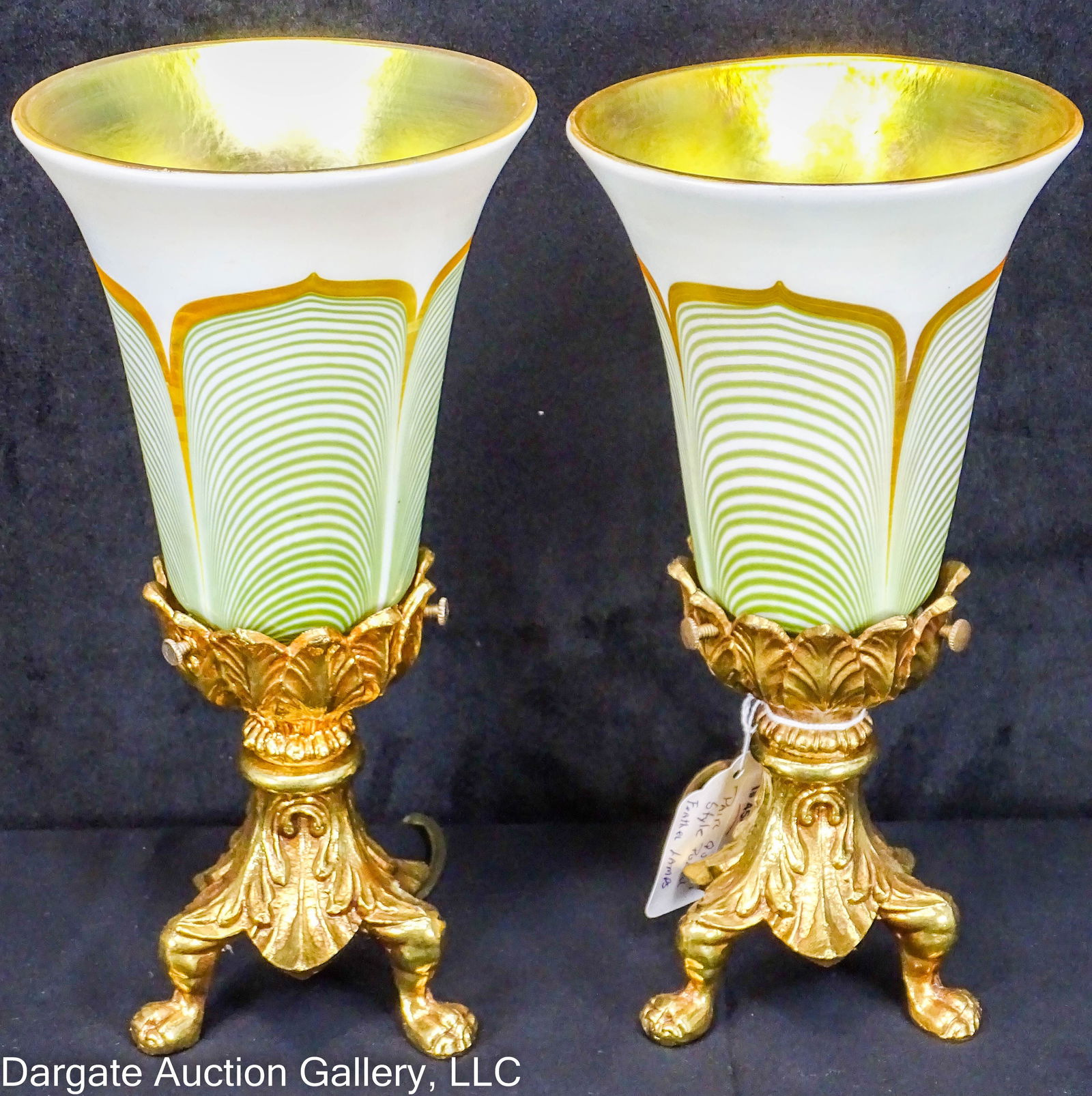PAIR QUEZAL STYLE PULLED FEATHER MANTLE LAMPS: Pair of brass mantle lamps with unsigned art glass shades, Quezal style, pulled feather exterior, and a gold aurene interior. Brass bases have 3 paw feet and ancanthus leaf decorations / Measures: 9.5