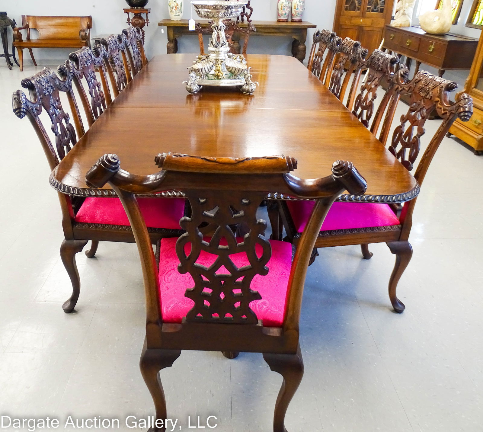 11pc MAHOGANY CHIPPENDALE DINGING ROOM TABLE SET: 20th Century carved Mahogany Chippendale dining room table and chair set; includes: 10 side chairs with a floral foliate scrolled back crest and splat, ball and claw feet and pink paisley seats (39.5&
