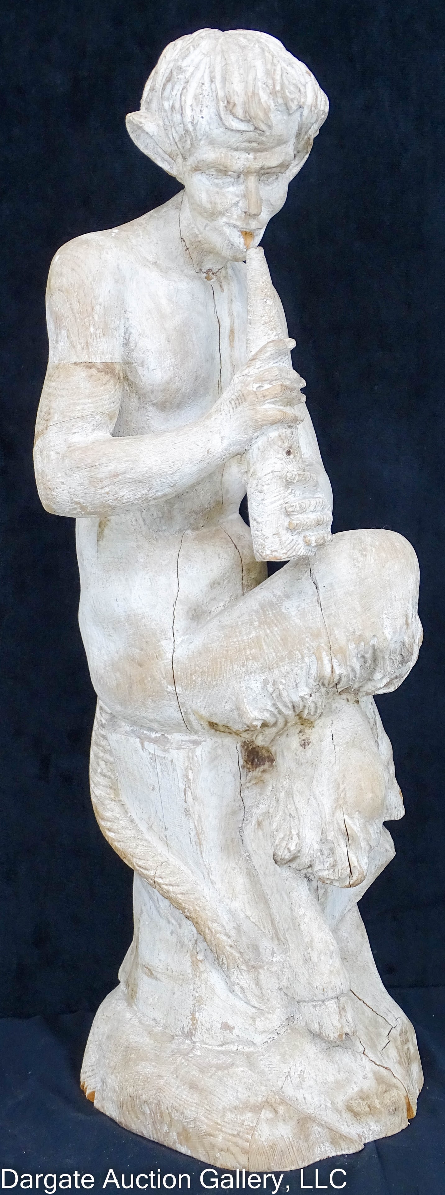 PAINTED CARVED WOODEN STATUE OF PAN: A painted and carved statue of Pan playing his flute sitting on a stump; carved from blocks of wood that have been glued together, then painted/whitewashed / Measures: 30.5"H x 10" diameter / Conditio