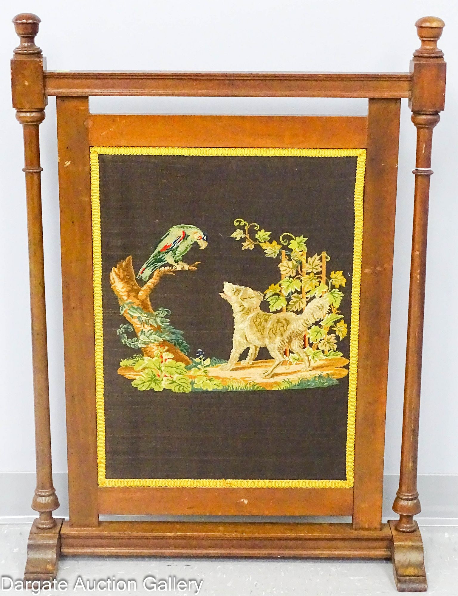 VICTORIAN STYLE MAHOGANY FIREPLACE SCREEN: Mahogany frame with turned wooden uprights and carved finials. Embroidered front panel with parrot on stump and barking dog by grape arbor; Measures: 36.5"H x 26"W x 8.5"D; Condition: m