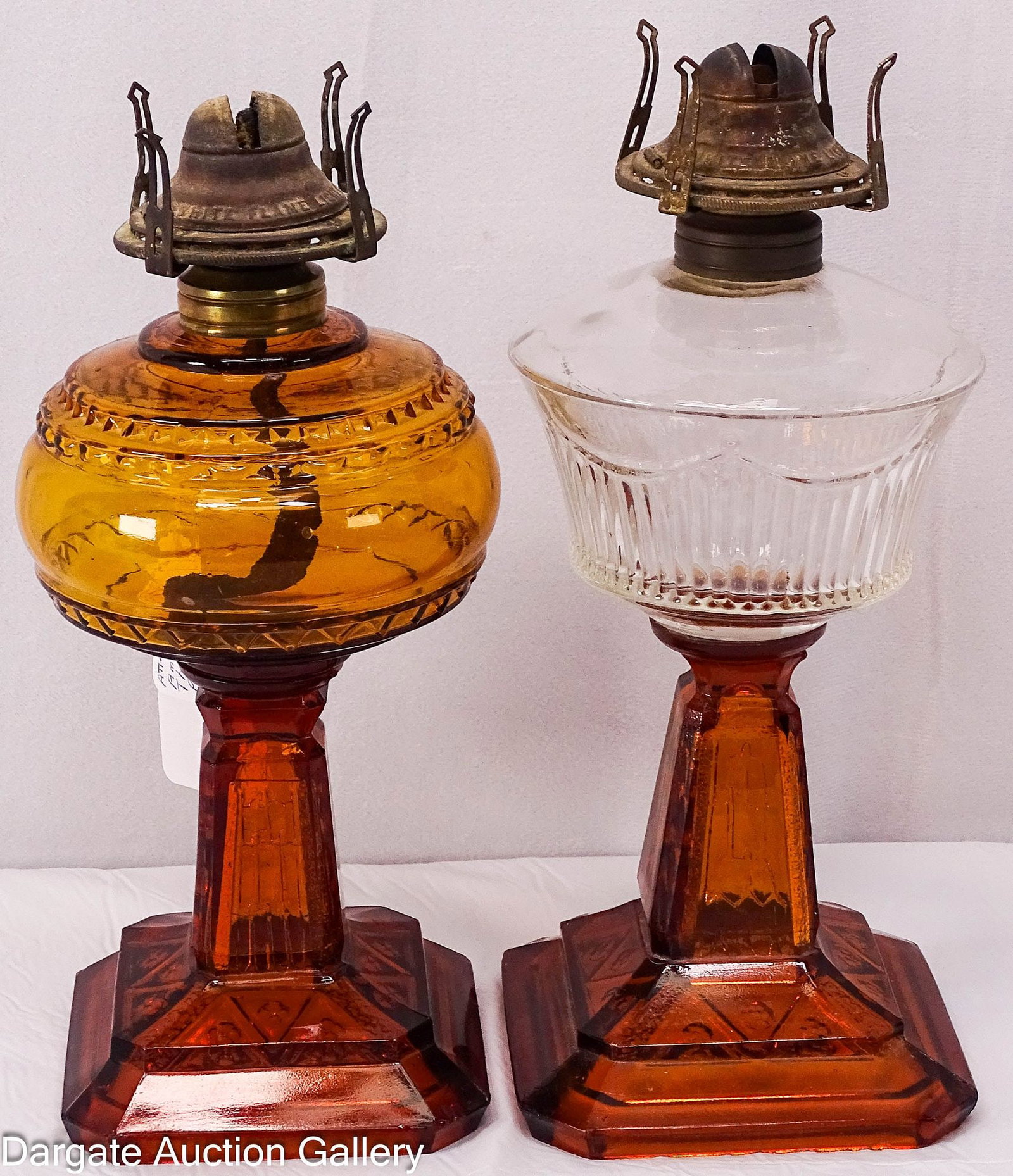 (2) ATTERBURY GEM LAMPS: 2 Atterbury & Company 19th Century stand oil lamps; both with Amber Star or Star & Column bases; one has a clear glass ribbed pattern font and the other has an amber font; #1 burners marked [W
