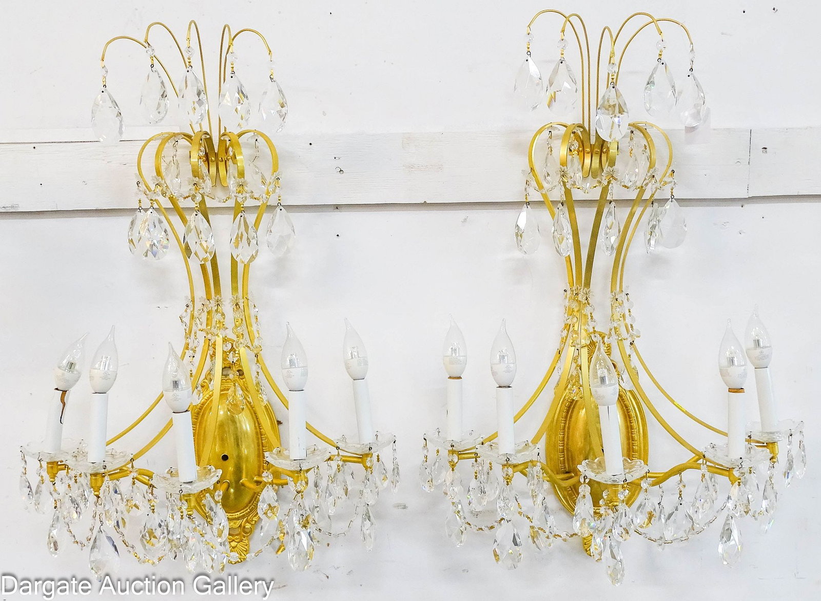PAIR MODERN GOLD FINISHED CRYSTAL WALL SCONCES: Pair of wall sconces in Hollywood Regency/Louis XVI Style; marked on back [TRADITIONS DESIGN GROUP]; sconces feature an oval base with flat metal scroll work, from the candle lights to the top;