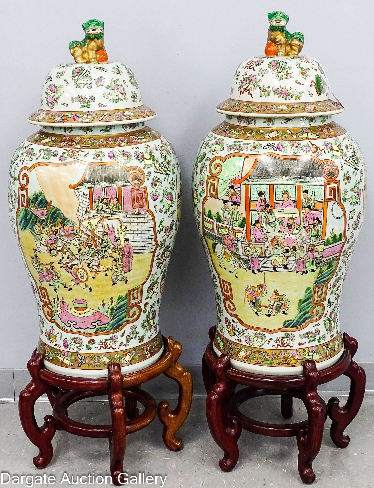 PAIR OF CHINESE FAMILLE ROSE FLOOR GINGER JARS ON STANDS: A monumental pair of Chinese Famille Rose ginger jars on hardwood stands; Foo dog finials with floral decorations, fans, books and scrolls. Featuring large cartouches depicting court life; Measures: 3