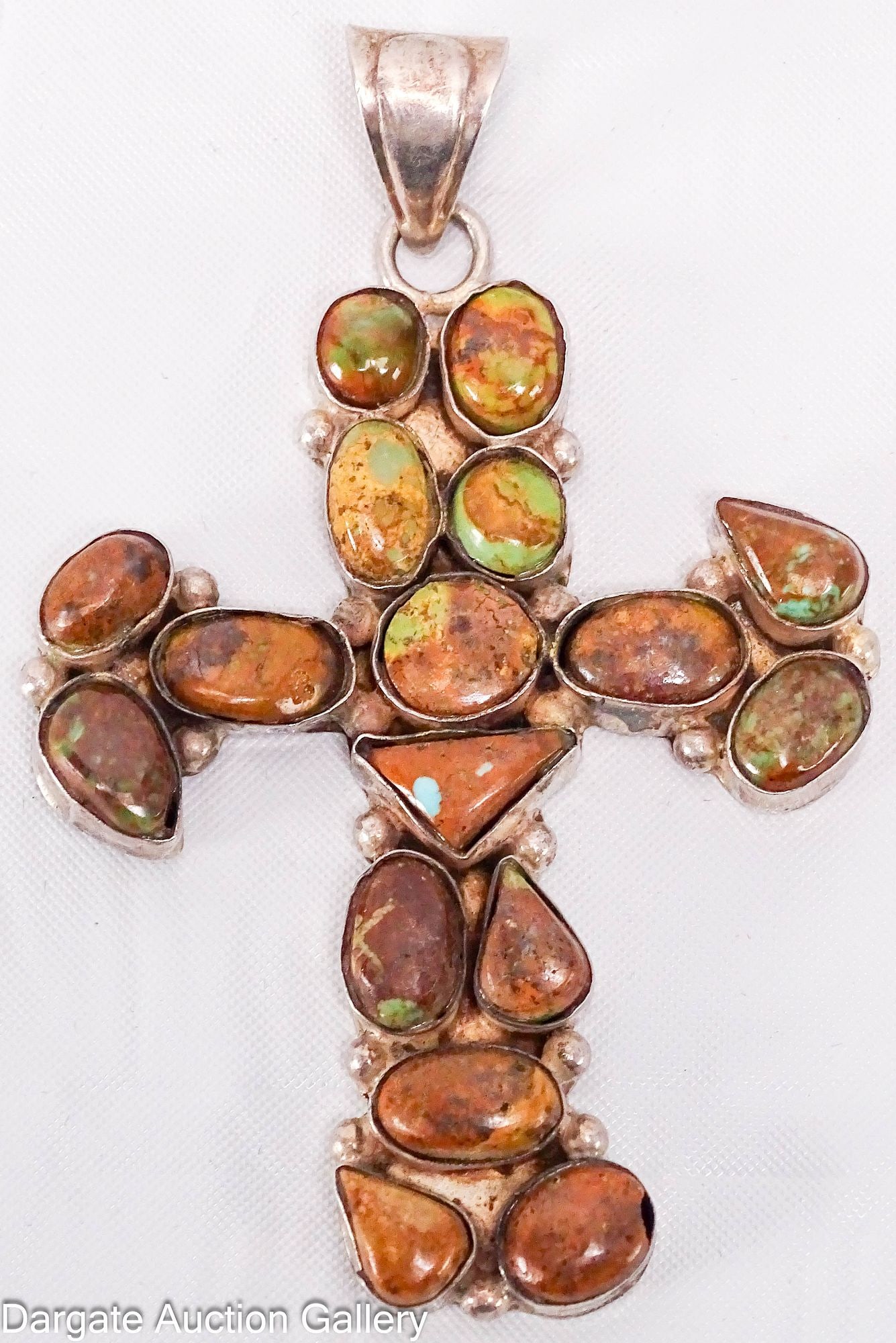 NAVAJO STELRING AND TURQUOISE CROSS PENDANT: Sterling silver cross set with 17 turquoise in browns and greens [925] (marked on bail, worn); Measures: 3"H x 3"W, Total gross weight - 19.7g