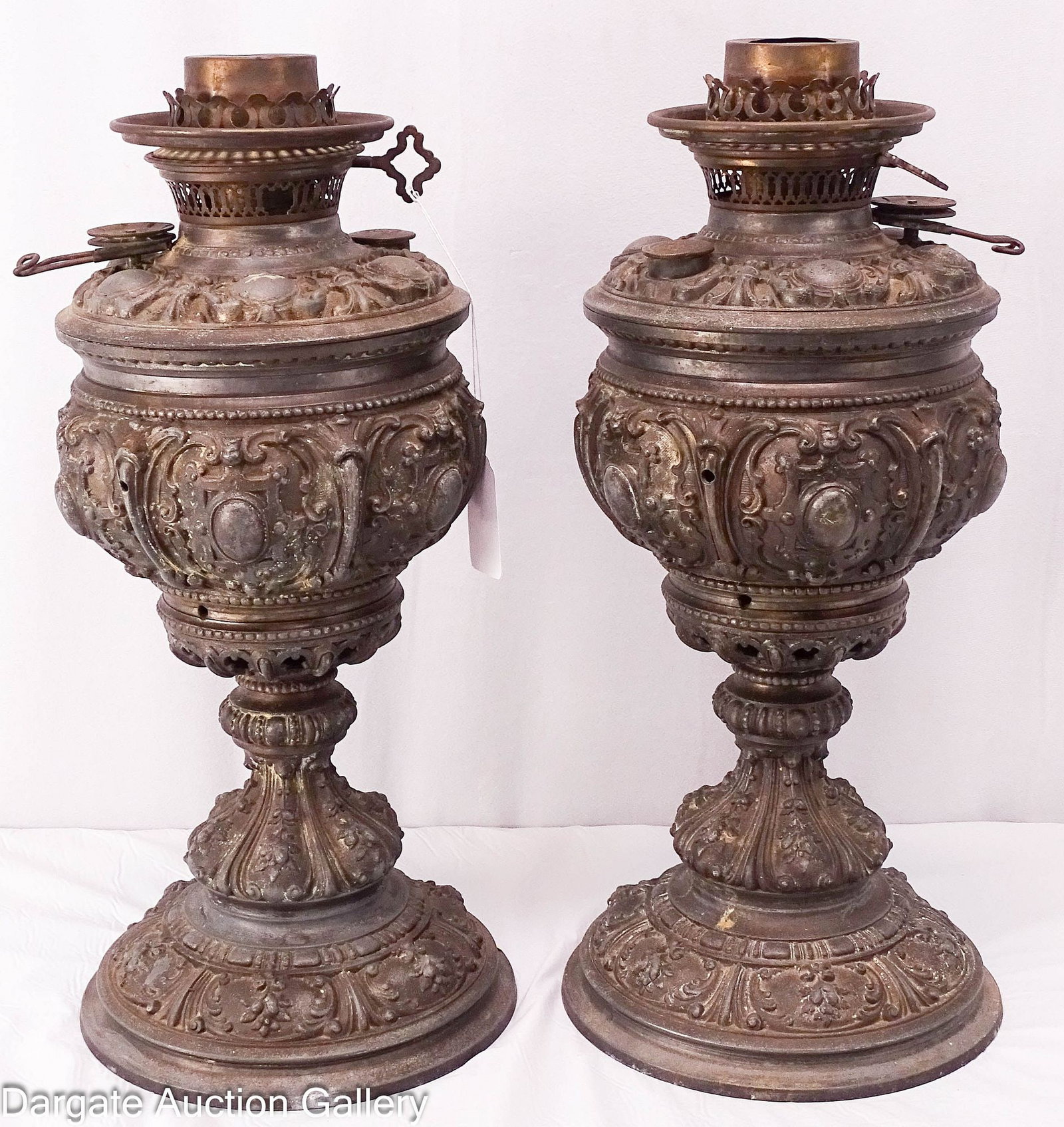 PAIR ROCOCO REVIVAL SPELTER TRIUMPH OIL LAMPS: Large ornate pair of Britania-Spelter metal oil lamps; circa late 19th Century with a pewter finish look, removeable fonts are brass with fancy spelter tops and still retain the original burners and s