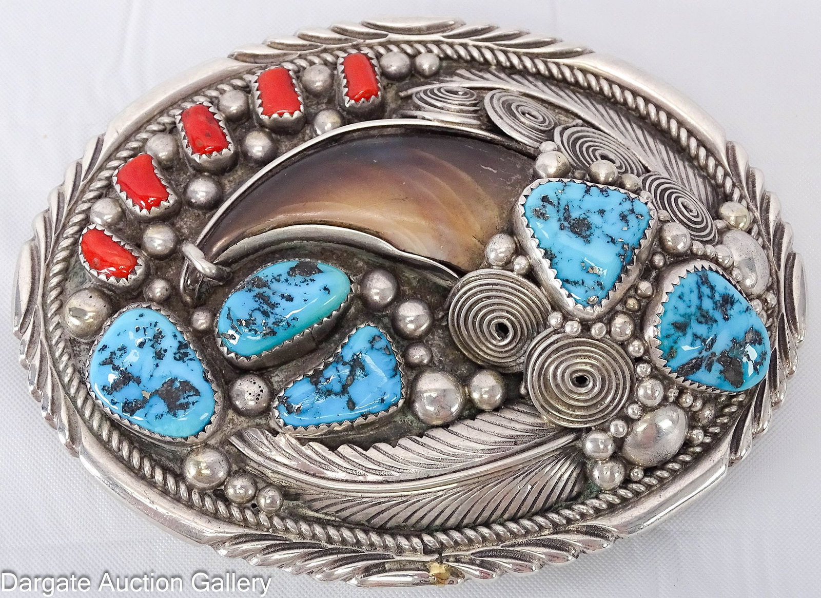 ELAINE SAM NAVAJO STELRING BEAR CLAW BELT BUCKLE: Oval belt buckle set with a bear claw, turquoise and coral in a Southwestern design of feathers, swirls and beads. Marked on back [NAVAJO / HANDMADE / ES] Not marked Sterling; Measures: 2 5/8"H x