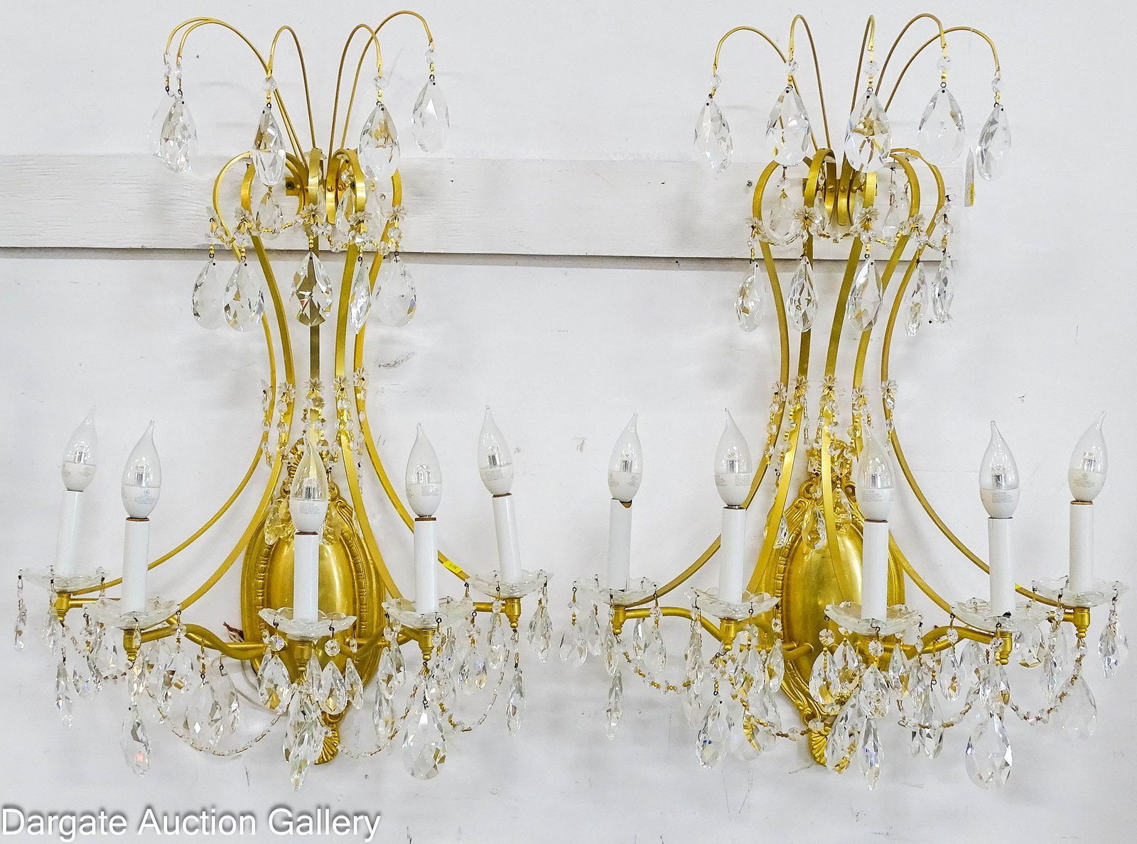 PAIR MODERN GOLD FINISHED CRYSTAL WALL SCONCES: Pair of wall sconces in Hollywood Regency/Louis XVI Style; marked on back [TRADITIONS DESIGN GROUP]; sconces feature an oval base with flat metal scroll work, from the candle lights to the top;