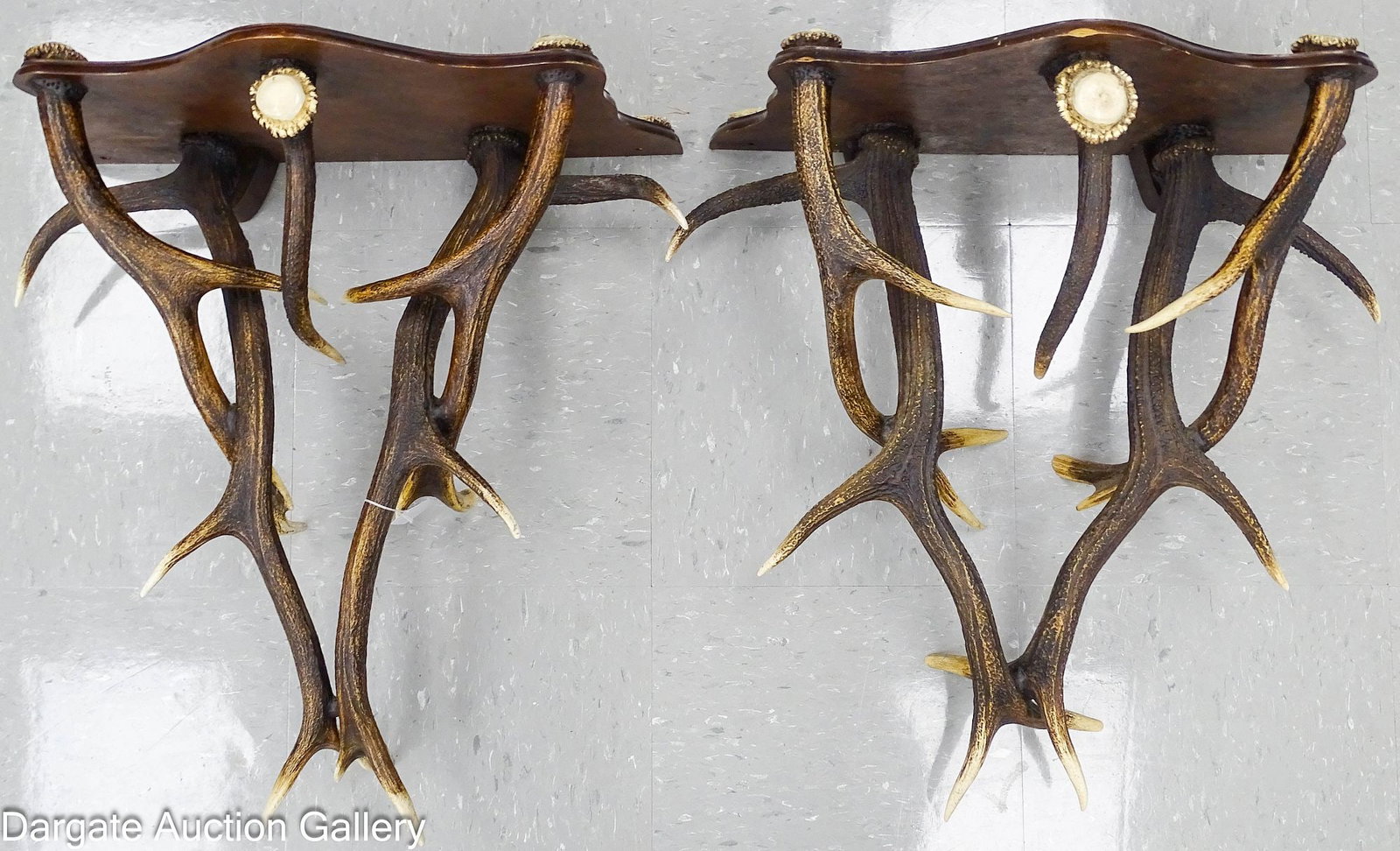 PAIR OF RUSTIC ELK HORN WALL SHELVES: A well-executed pair of wall shelves made of laminated hardwood and stained elk antler with reinforced wooden hangers. The ends of the antlers have been polished and the shelf tips have polished elk
