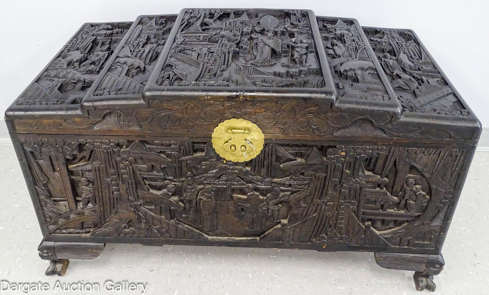 CHINESE CARVED CAMPHOR WOOD CHEST: Chinese wood chest with a stepped top and deeply relief carved panels depicting traditional mythological scenes, figures, landscape and architecture; sits on 4 paw feet with a face carver on top, roun
