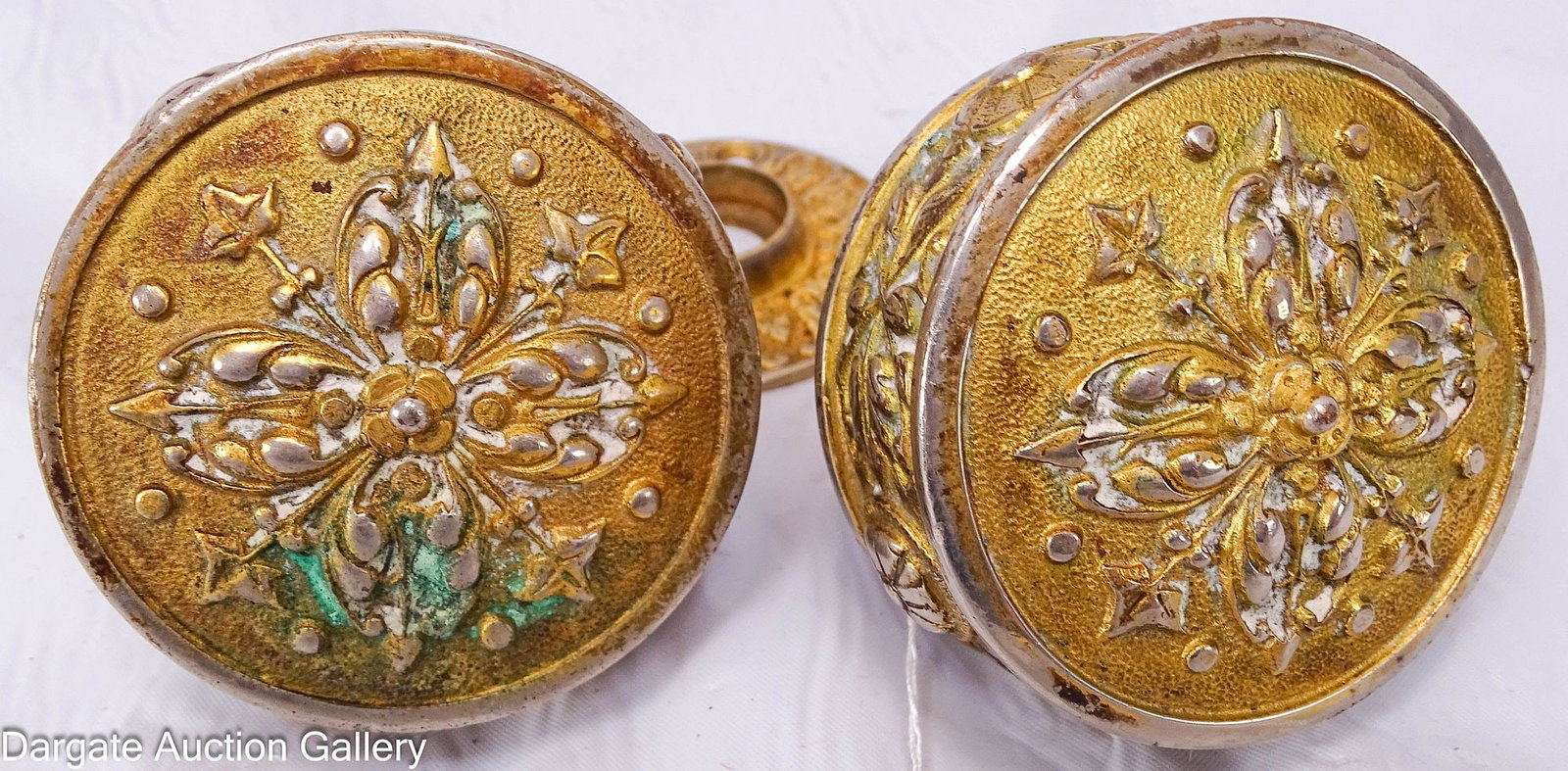 PAIR OF DRUM-STYLE P.F. CORBIN VICTORIAN DOOR KNOBS: A pair of gilt metal door knobs in a drum style with small round back plates. Patented May 29, 1877, the design features scrolls, rosettes, and decorative scrollwork. / Dimensions: 3&