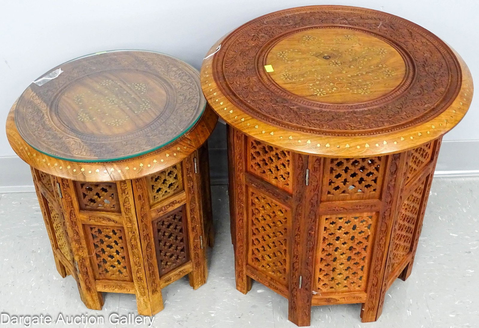 (2) PIERCED CARVED MOROCCAN STANDS with INLAY: (2) Octagonal Teak wood foldable table stands with pierced carvings and floral designs; these have brass and copper inlay on round tops; Measures: Larger - 18.75"H x 18" diameter, Smaller - 