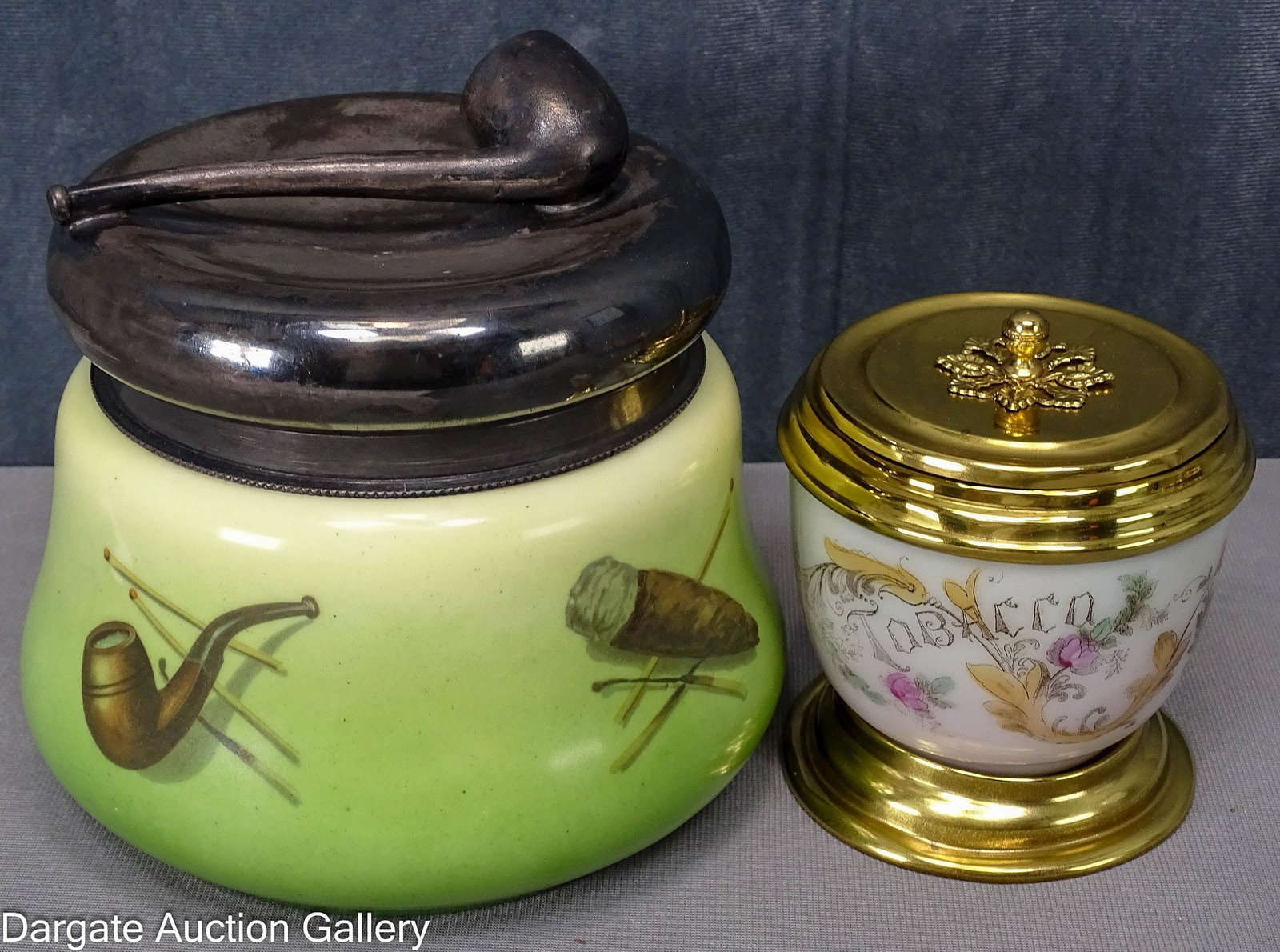 (2) EARLY 20th CENTURY GLASS HUMIDORS: Includes: Unmarked Schwarzburg Germany glass humidor featuring cigars, a pipe, a cigarette and matches, on a green background with a silver plated lid with a pipe finial, 6"H x 7" diameter (