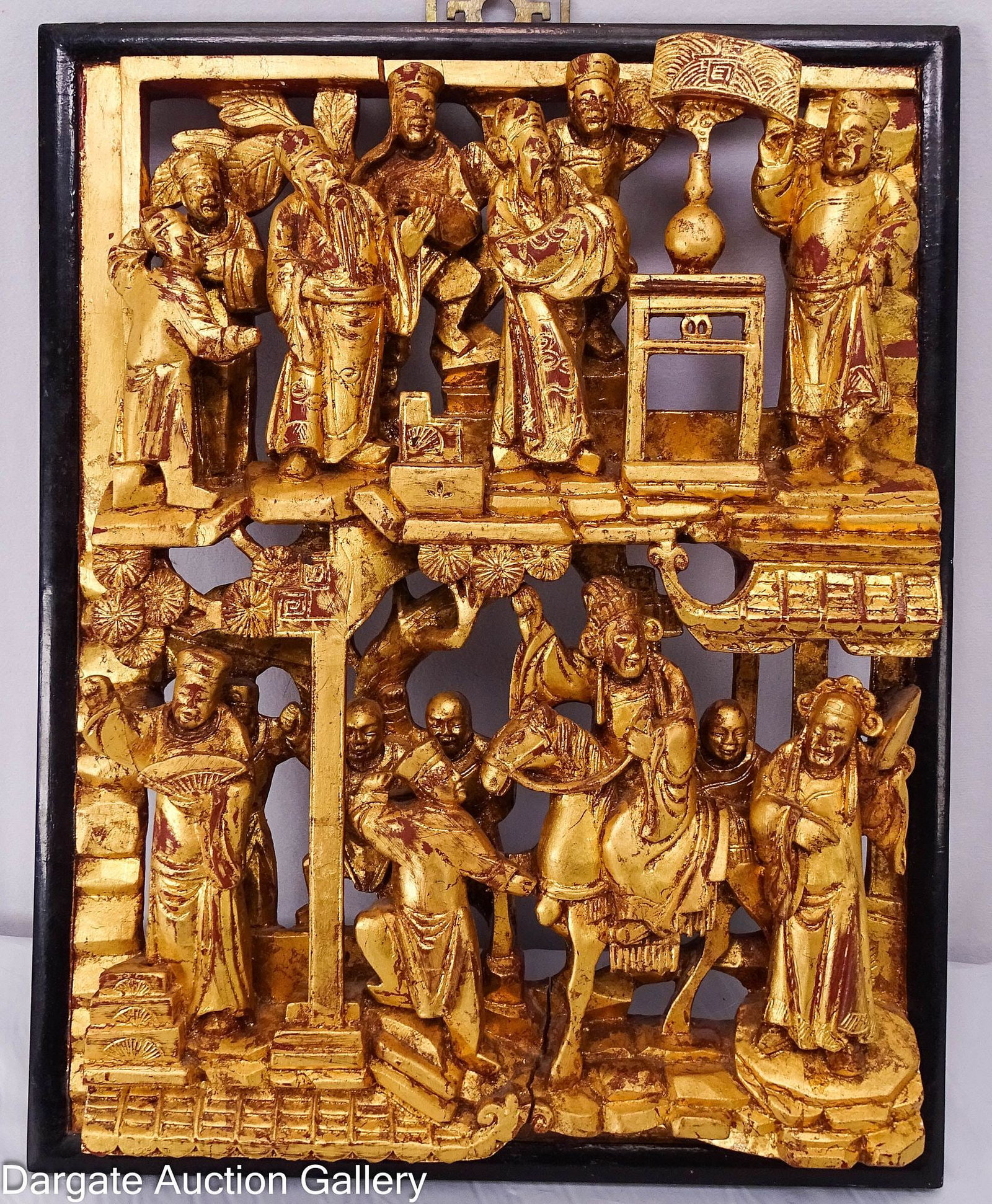 ANTIQUE CHINESE CARVED PANEL CHAOZHOU WOOD CARVING: Intricate high-relief scene of scholars and mythical deities in a village with trees and a figure on a horse. Features gold gilt over red lacquer and is mounted in a later black lacquer frame for hang