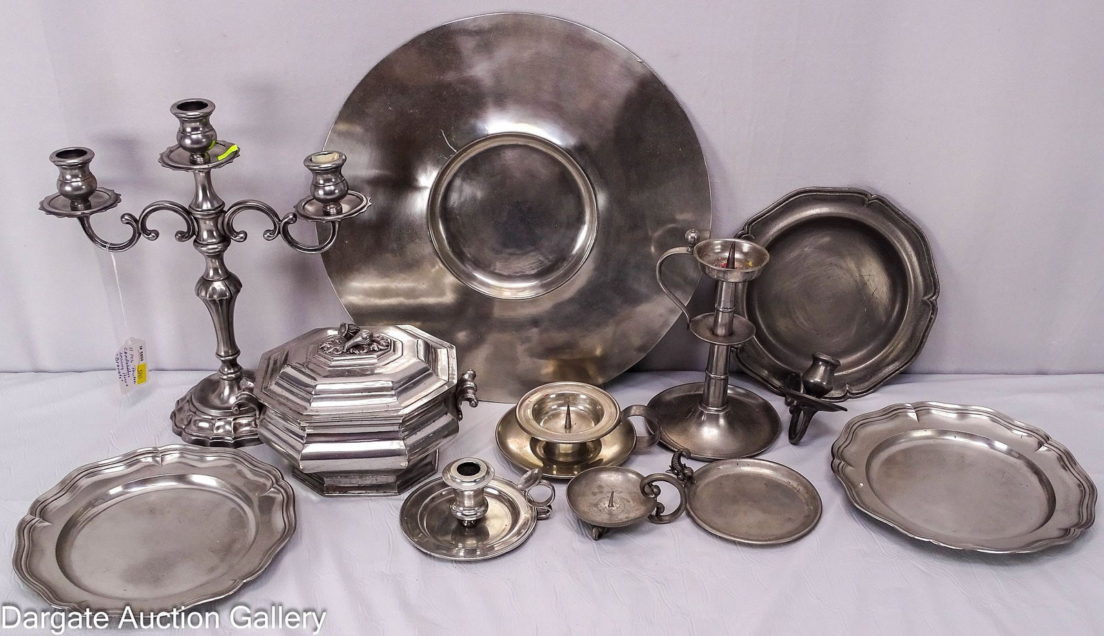 11pcs PEWTER INCLUDING CANDLE HOLDERS AND SERVING PIECES: Includes: a wall mount charger with many dents and bends 15" diameter (5) Candle holders including a 12.75"H candelabra 2.25"H chamberstick - personalized "Brandt 1962) for