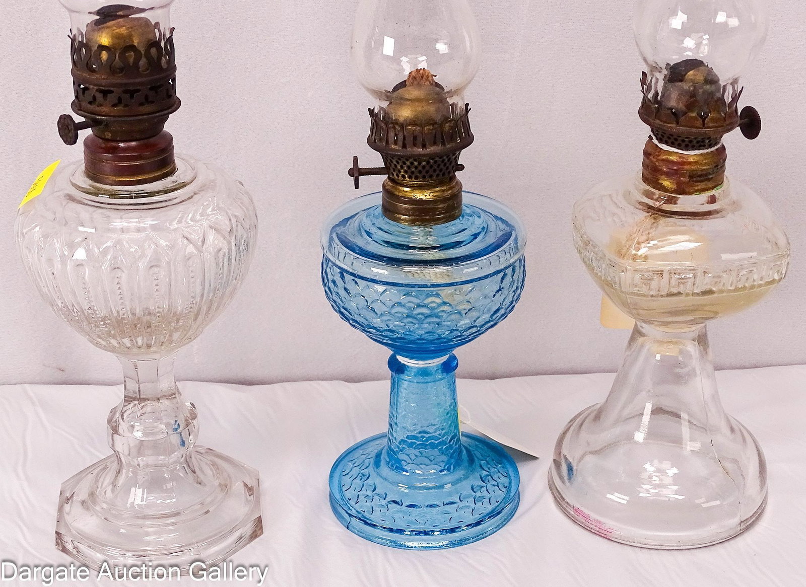 (3) MINIATURE OIL LAMPS: Three Victorian miniature oil lamps: 1) Light blue glass with fish scale pattern and Hornet burner; 2) Clear glass with Greek key pattern and Acorn burner (chimney appears new); 3) Clear glass with zi