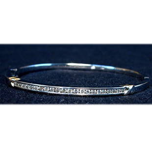 14K DIAMOND BANGLE. The white gold bang: 14K DIAMOND BANGLE. The white gold bangle has a row of round cut diamonds flanked on each side by yellow gold "criss-crosses". Total diamond weight is approximately 1.0 ct. Total bangle weight is