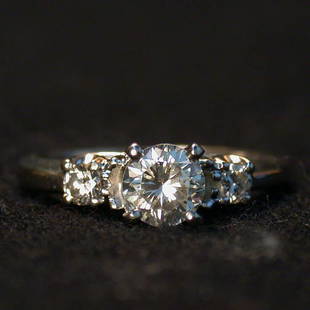 14K THREE DIAMOND RING. The ring has a: 14K THREE DIAMOND RING. The ring has a .60 ct. center stone flanked on both sides by smaller stones mounted in a 14K white gold setting.