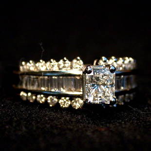 14K DIAMOND SOLITAIRE. The princess cut: 14K DIAMOND SOLITAIRE. The princess cut center stone is flanked on both sides by round and emerald cut diamonds mounted in a white gold setting. Total weight of the diamond mount is approximately 1.0
