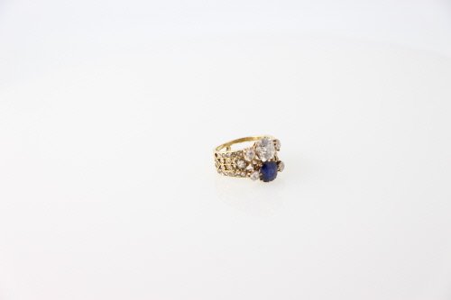 Bijoux: BAGUE en or jaune 18 K (750Â°/00) formÃ©e de deux anneaux ajourÃ©s ornÃ©s de diamants taille rose, serti griffe, rehaussÃ© d'un diamant de taille ancienne, env.1 carat, et d'une pierre bleue
