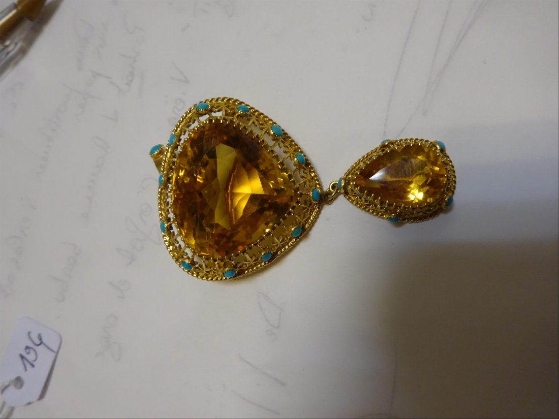 Bijoux: BROCHE formant pendentif en or jaune 18K (750%o) sertie griffes de deux importantes citrines taillÃ©es en poire, entourÃ©es de filigranes retenant des pierres bleues (imitant la turquoise). Poids