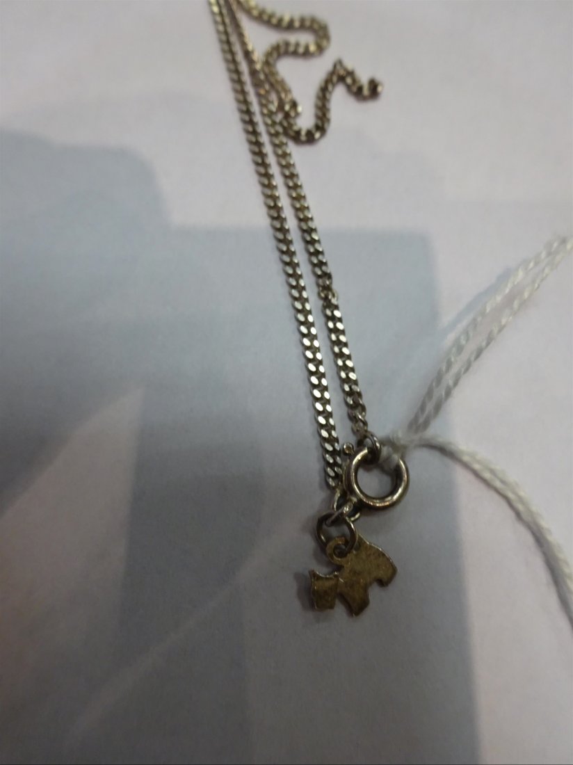 Bijoux: COLLIER RAS DU COU en argent (?) retenant un pendentif en forme de Scottish-Terrier. Poids brut: 5 g. L (totale): 38,5 cm (pendentif lÃ©gÃ¨rement pliÃ©) DROIT AU CONTROLE