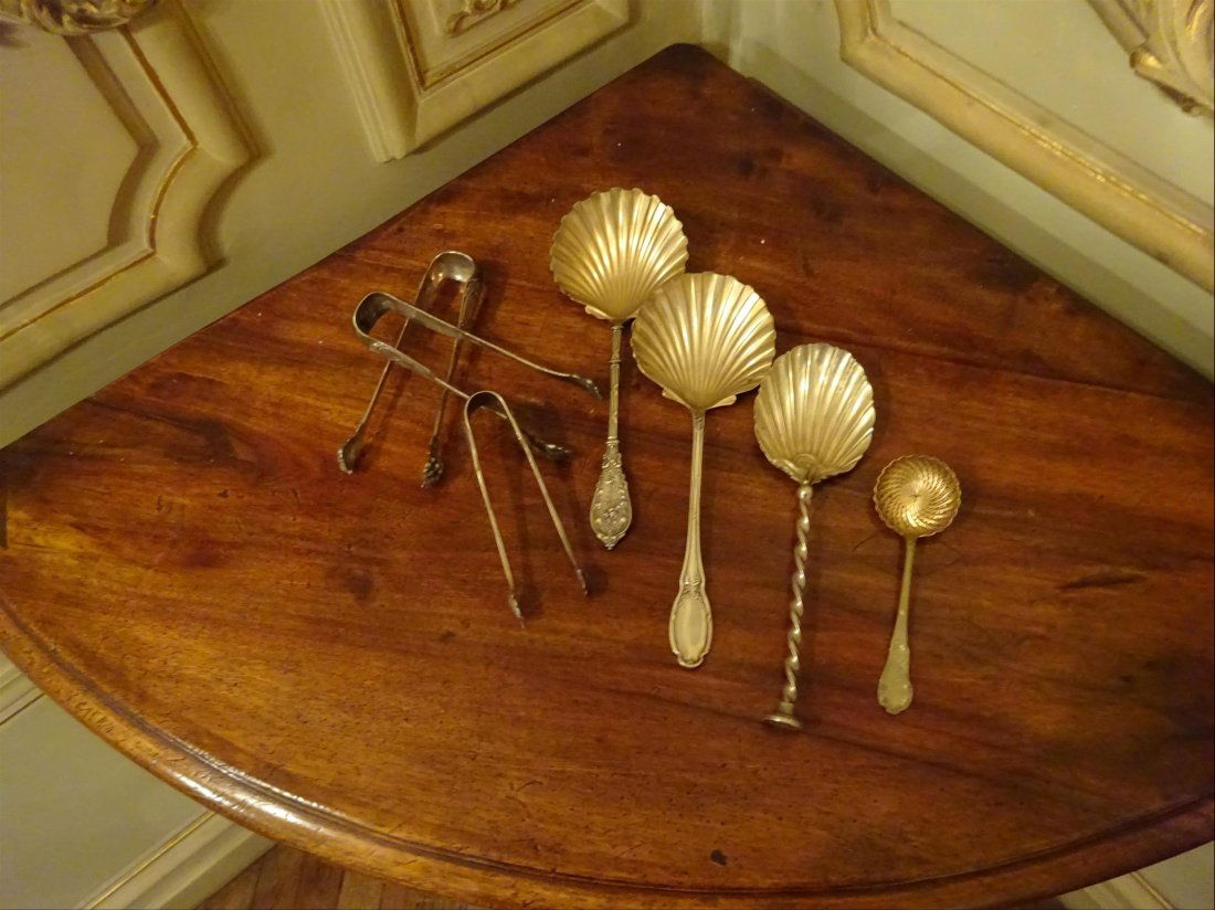 Argenterie: ARGENT - Lot comprenant : > 1 saupoudreuse ; > 3 grandes cuillers aux cuillerons stylisant une coquille Saint Jacques ; > 3 pinces sucre. Poids brut total approximatif : 427 g.