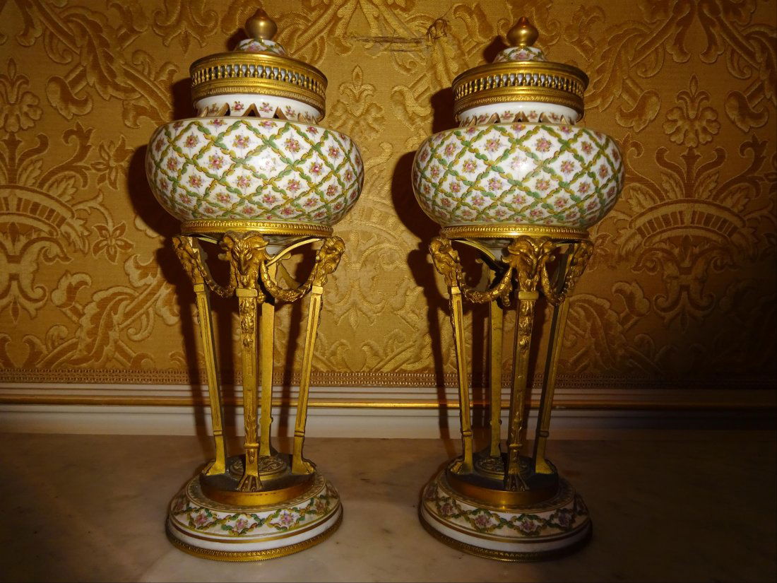 Objets d'Art: Paire de CASSOLLETTES en porcelaine mont(e)s en bronzes formant athniennes. Elles reposent sur quatre montants termins par des ttes de bliers aux guirlandes de laurier. Dans le got de Svres. H : 30 cm