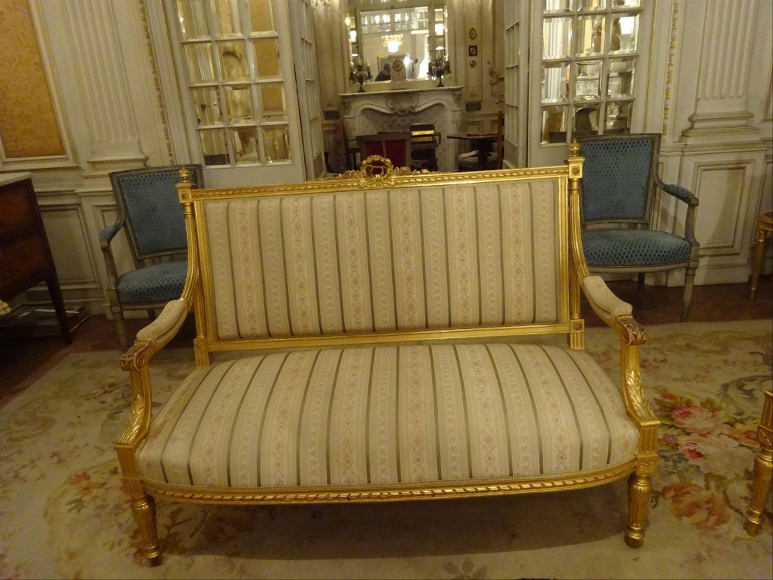 Mobilier Ancien: MOBILIER DE SALON de style Louis XVI en bois moulur, sculpt et dor dcor de feuillages, guirlandes de roses, plumets fleuris et rosaces stylises. Il comprend deux canaps, deux fauteuils et deux chai