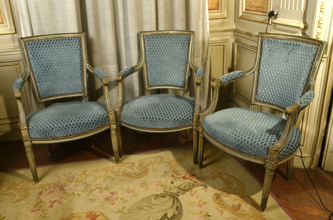 Mobilier Ancien: Suite de trois FAUTEUILS dossiers cabriols en bois moulur, sculpt et laqu crme. Supports d'accotoirs fouetts. Ils reposent sur des pieds fusels cannelures rudentes. Fin de l'poque Louis XVI (usu