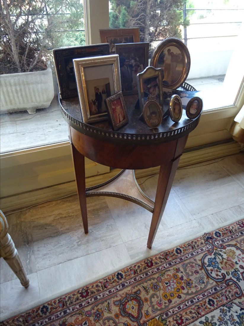 Mobilier Ancien: TABLE BOUILLOTTE en acajou et placage d'acajou reposant sur trois pieds gaines entretoise vide ; dessus de marbre gris ceint d'une galerie en laiton. Travail des annes 1900 (accidents et insolation