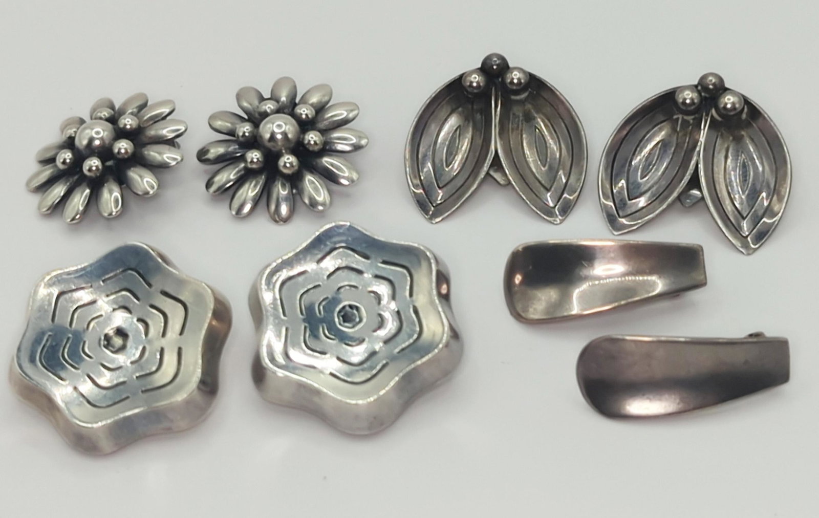 VARIOUS MAKERS, DENMARK; Four Pair Modernist Sterling Earrings: 20th century. Brdr. Bjordkland 1" concave design, A. Dragsted 1 1/4" petal design, S. Chr. Fogh 1" daisy design, A.B.K. 1" floral design (one clip needs to be re-attached), 40 grams. Good condition.