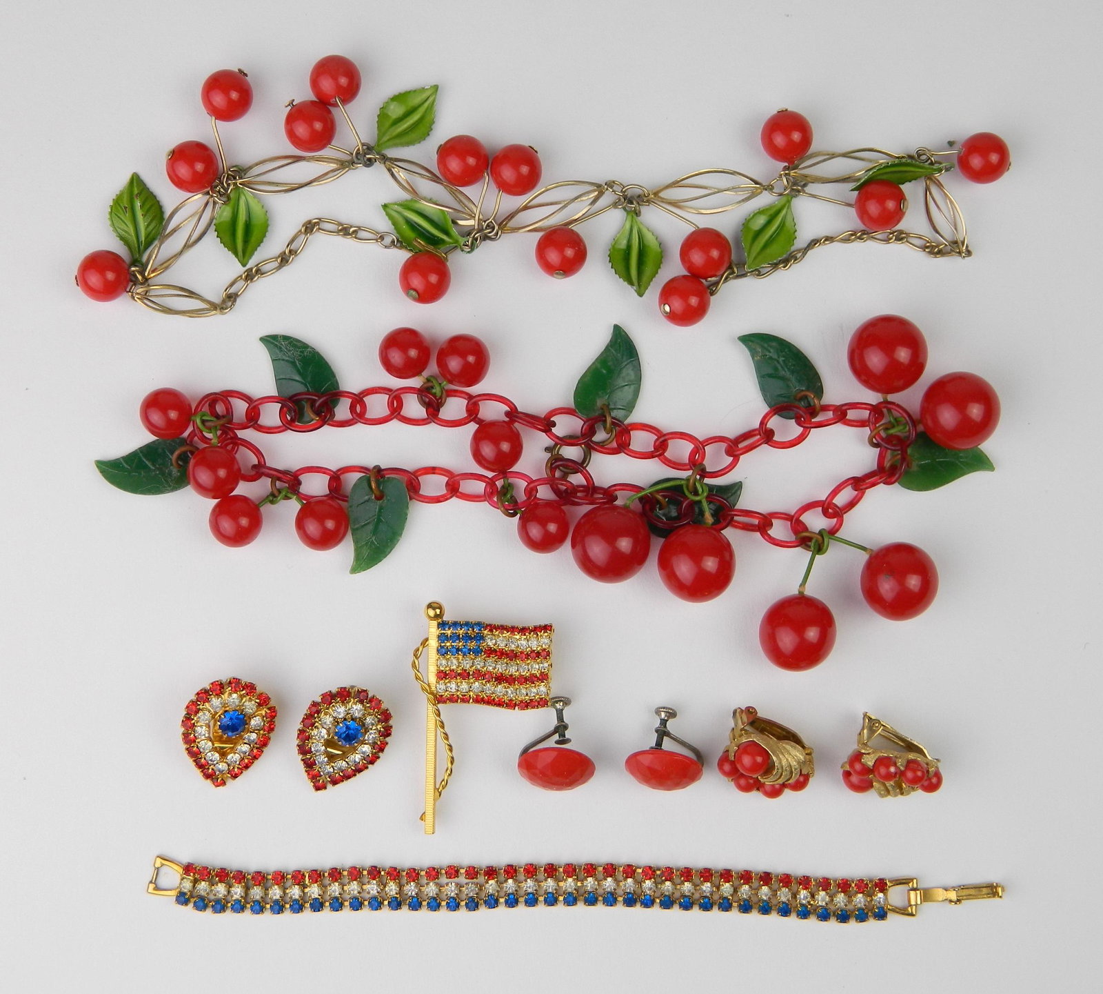 Costume jewelry: Costume jewelry- Patriotic set including a flag pin, pair of sweater clips and a bracelet together with a necklace of cherries and a double row bracelet of cherries (possibly Bakelite).