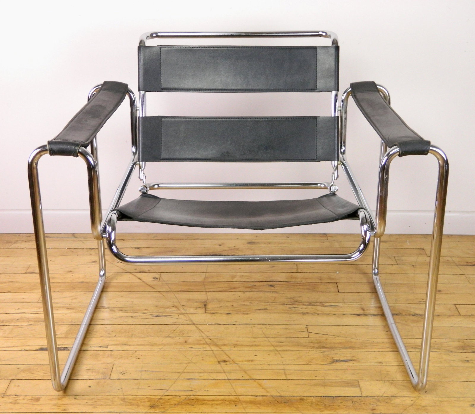 Marcel Breuer style chair: after Marcel Breuer- Wassily chair, black leather chair with chrome tubular frame, seat is splitting on underside. 28 x 28 x 31''