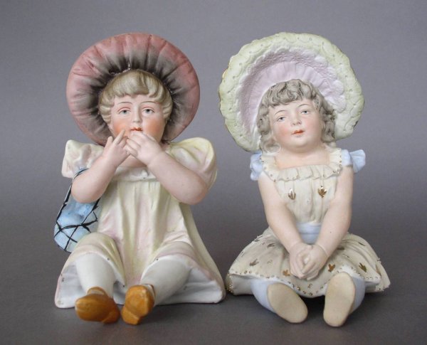 Bisque hand-painted figurines: 2 Bisque hand-painted figurines- Seated Girls in Bonnets. 7''