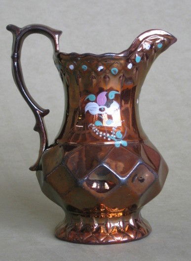 Copper lustre pitcher: Copper lustre pitcher with hand-painted flower decoration, faceted body, chip on spout and areas of paint loss, otherwise good condition. 7 1/2''h