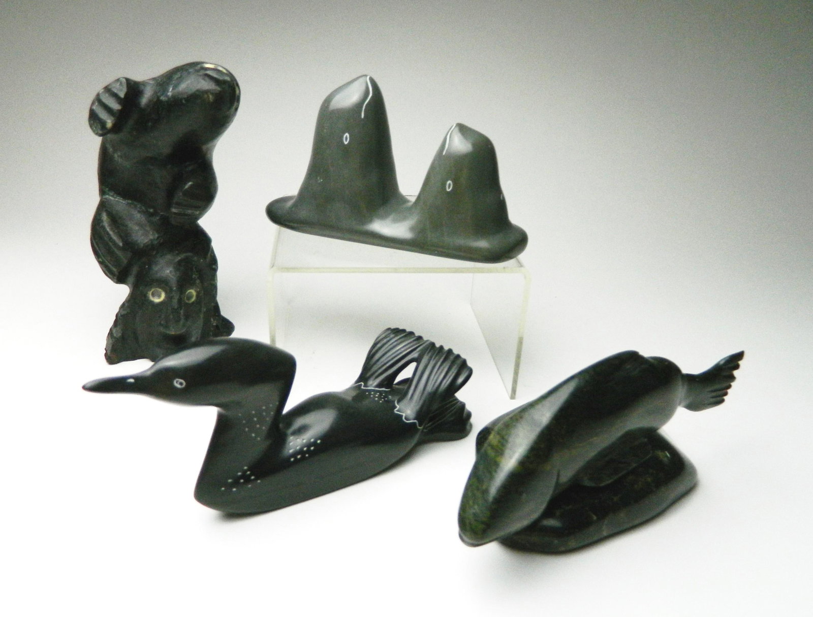 4 Inuit stone carvings: 4 Inuit stone carvings 1). Lucas Aaluk / Gjoa Haven- Head and Soul- 2004, signed and dated; 2). Sheokjuk Carriere- Beluga Whale- signed; 3). Chesley Short / Cape Dorset- Playful Fish; 4). Jacob Uppik 
