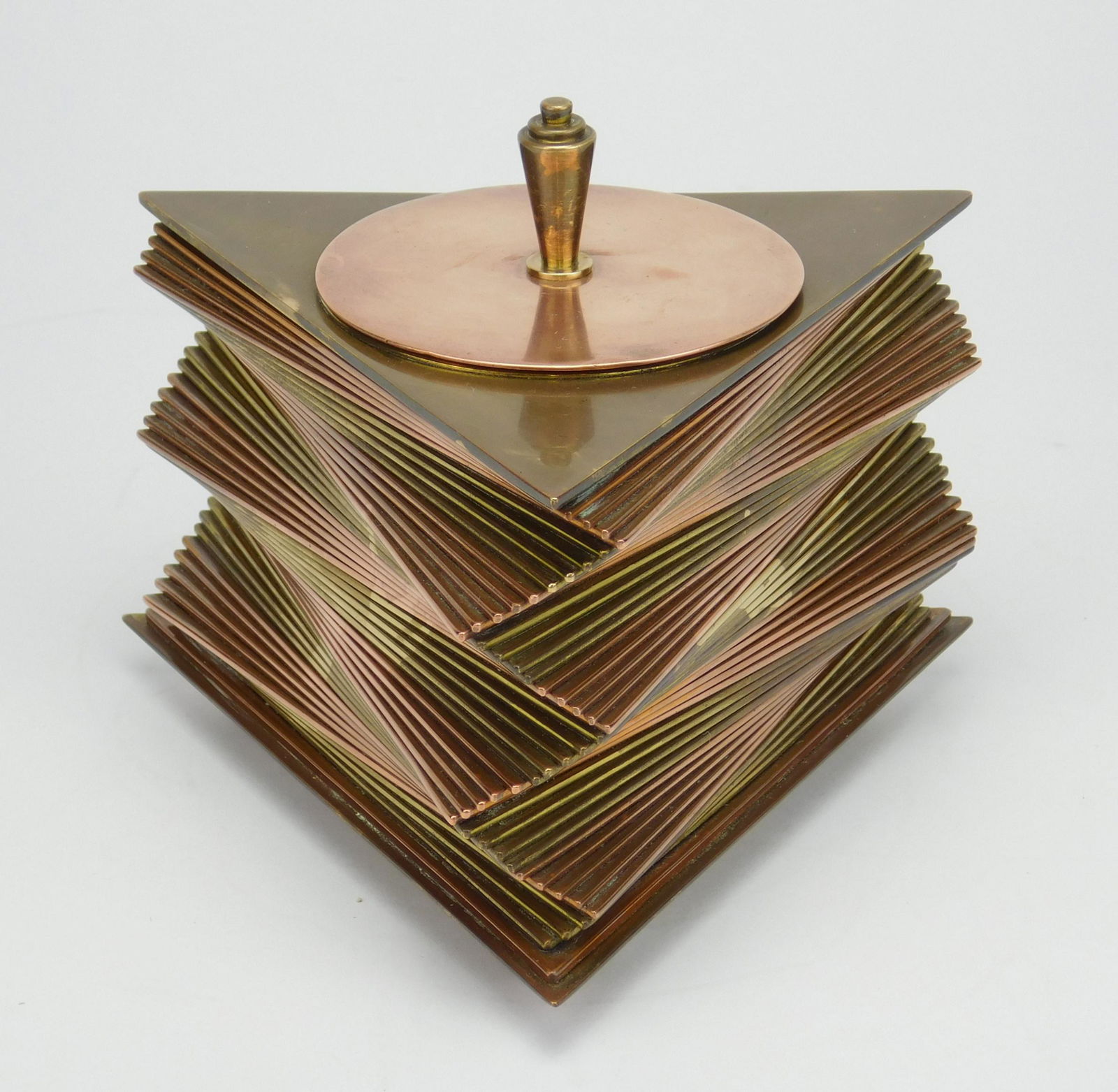 John Otar brass and copper box: John Otar Art Deco brass and copper cigarette box, ca. 1928-1935, designed, patented and produced by John Otar . The box is composed of individual triangular brass and copper plates, stacked to create