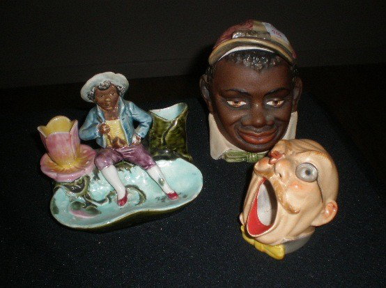Majolica humidor, ashtray and matchstick holder: Majolica humidor, in the form of a black jockey; together with a whimsical ashtray of a head of a man being stung by a bee; and a Majolica matchstick holder of a black man by tree truck and flower, no