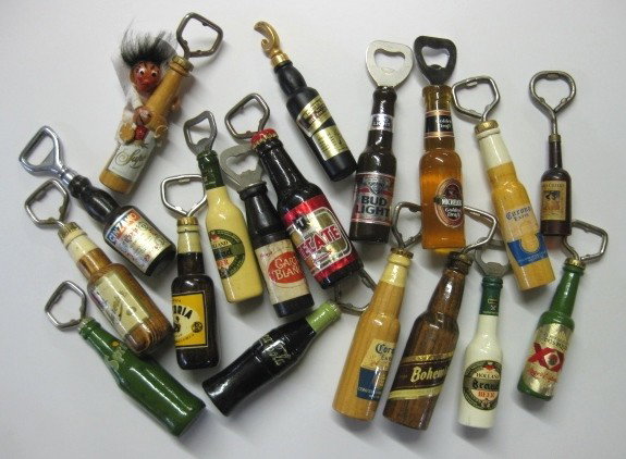 18 Bottle openers- soda and beer bottles form: 16 Wooden and 2 plastic figural bottle openers- in form of soda and beer bottles, wear throughout, various sizes.