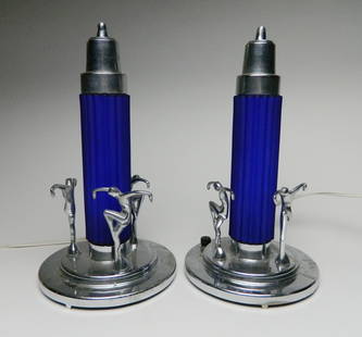 Pair of Art Deco chrome and blue glass lamps: Pair of Art Deco Skyscraper Table Lamp. Chrome plated base with 3 standing figural dancers around a blue satin glass cylindrical shade having a fluted form and a stepped conical top. note 1 figure is